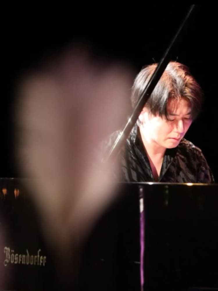 コンサートホールのステージで、グランドピアノを演奏するピアニストの福間洸太朗。