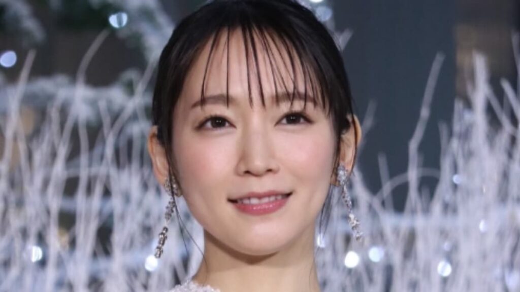 白いドレス姿で、冬のイルミネーションを背に微笑む吉岡里帆のポートレート写真。