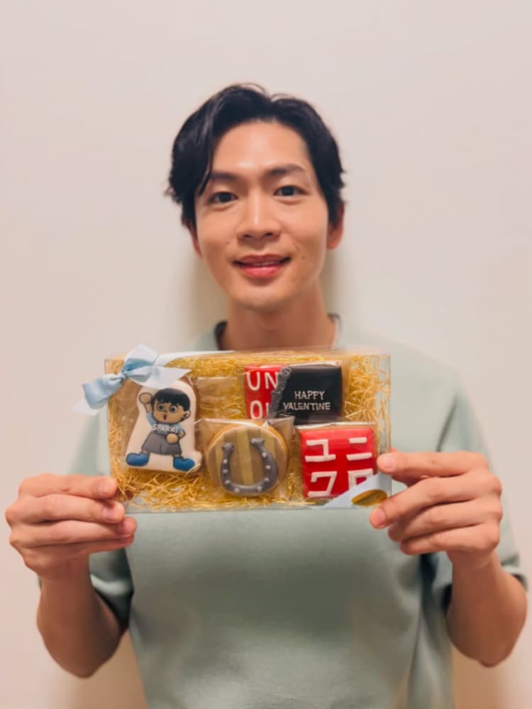 2026年バレンタインに向けて、公式アンバサダーを務めるユニクロ（UNIQLO）のロゴや馬蹄がデザインされた特製アイシングクッキーを手に、柔らかな笑顔を見せる松下洸平。